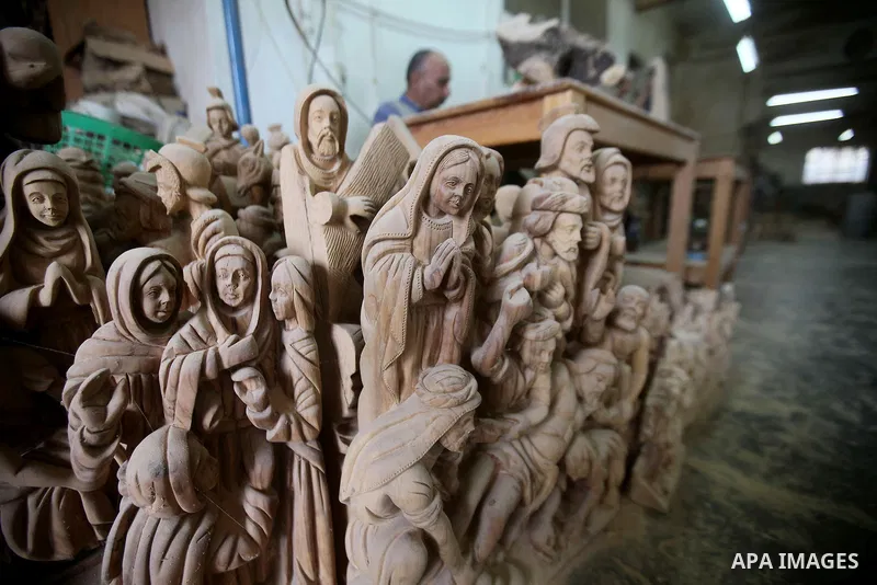 A Palestinian carpenter carves a wooden effigies of the the Holy Family at a workshop in the West Bank town of Bethlehem, on December 13, 2016. The traditional birthplace of Jesus Christ prepares to celebrate Christmas l...