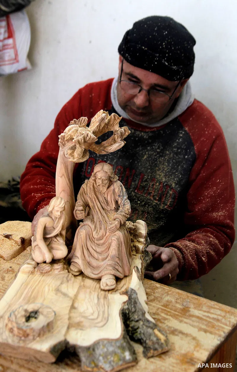 A Palestinian carpenter carves a wooden effigies of the the Holy Family at a workshop in the West Bank town of Bethlehem, on December 13, 2016. The traditional birthplace of Jesus Christ prepares to celebrate Christmas l...