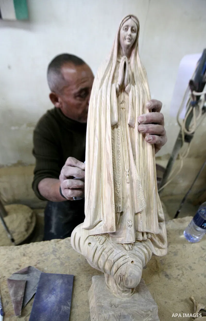 A Palestinian carpenter carves a wooden effigies of the the Holy Family at a workshop in the West Bank town of Bethlehem, on December 13, 2016. The traditional birthplace of Jesus Christ prepares to celebrate Christmas l...
