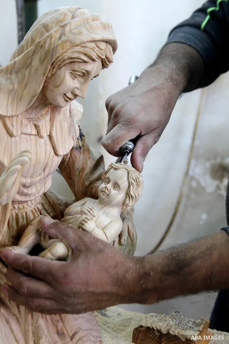 A Palestinian carpenter carves a wooden effigies of the the Holy Family at a workshop in the West Bank town of Bethlehem, on December 13, 2016. The traditional birthplace of Jesus Christ prepares to celebrate Christmas l...