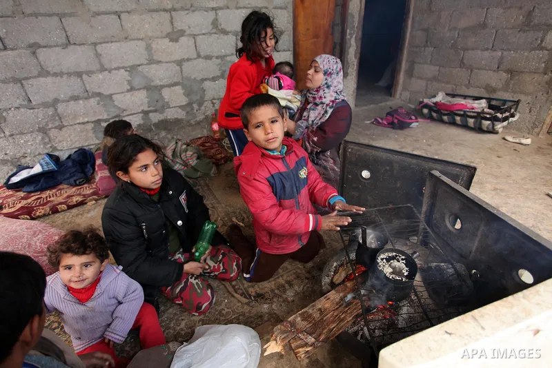 Palestinians warm themselves around a fire during the winter storm in Khan Younis, in the southern Gaza Strip on December 14, 2016. Photo by Ashraf Amra