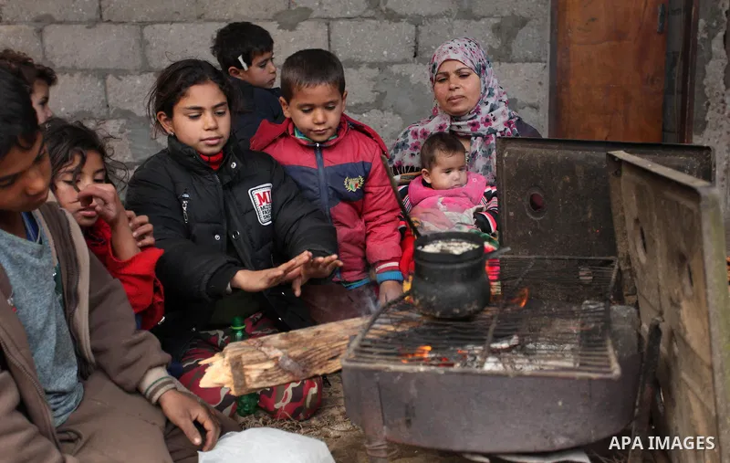 Palestinians warm themselves around a fire during the winter storm in Khan Younis, in the southern Gaza Strip on December 14, 2016. Photo by Ashraf Amra