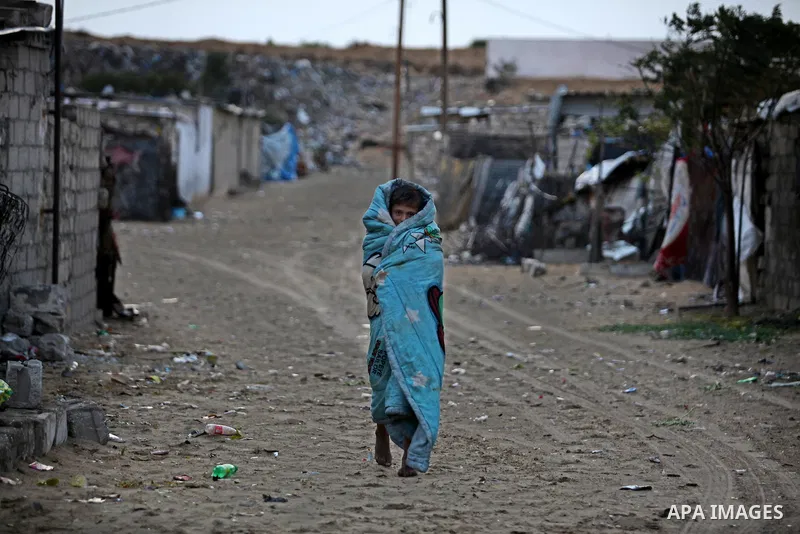 A Palestinian boy walks outside his family's shanty during the winter storm in Khan Younis, in the southern Gaza Strip on December 14, 2016. Photo by Ashraf Amra