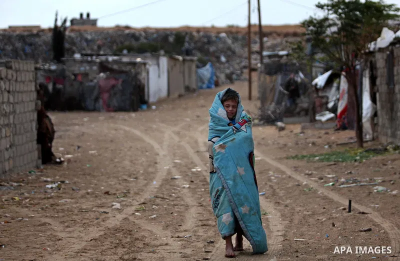 A Palestinian boy walks outside his family's shanty during the winter storm in Khan Younis, in the southern Gaza Strip on December 14, 2016. Photo by Ashraf Amra