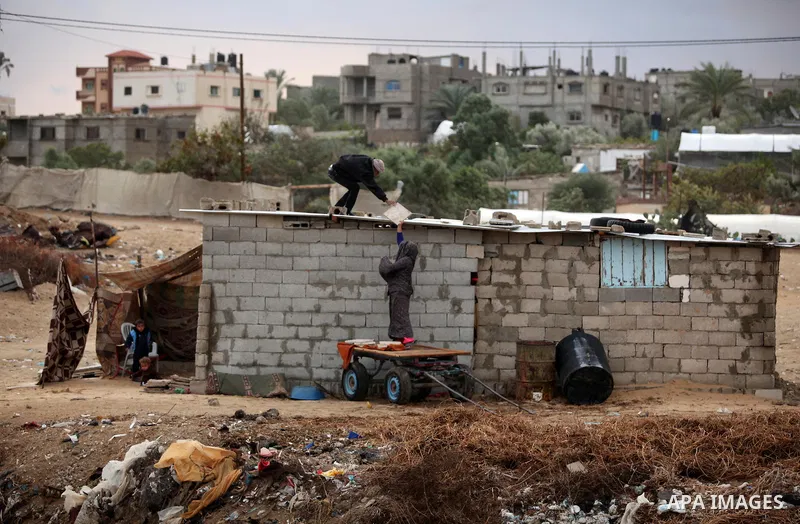 A Palestinian man and his wife repair their dwelling during the winter storm in Khan Younis, in the southern Gaza Strip on December 14, 2016. Photo by Ashraf Amra