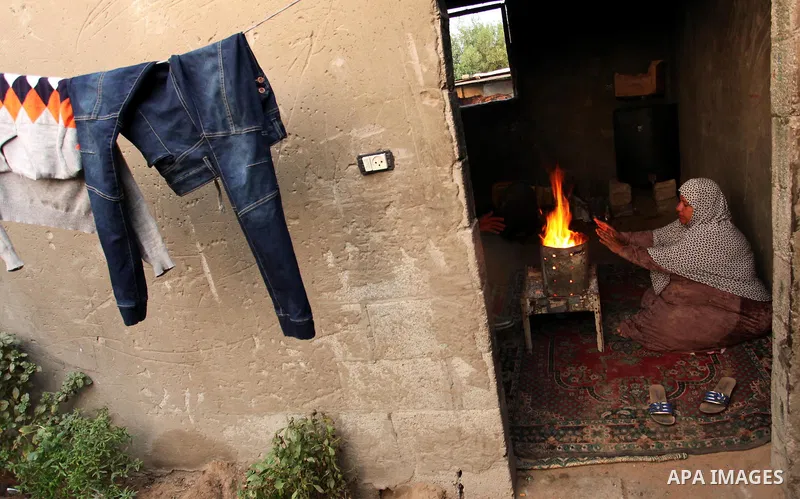 Palestinians warm themselves around a fire during the winter storm in Khan Younis, in the southern Gaza Strip on December 14, 2016. Photo by Ashraf Amra