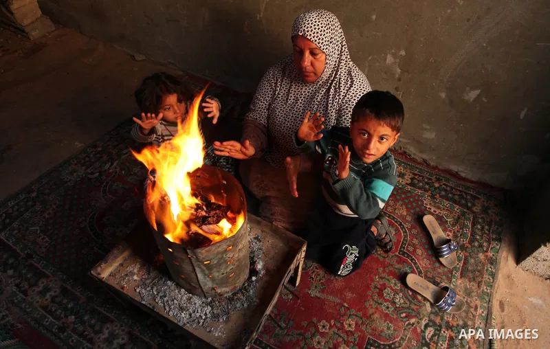Palestinians warm themselves around a fire during the winter storm in Khan Younis, in the southern Gaza Strip on December 14, 2016. Photo by Ashraf Amra