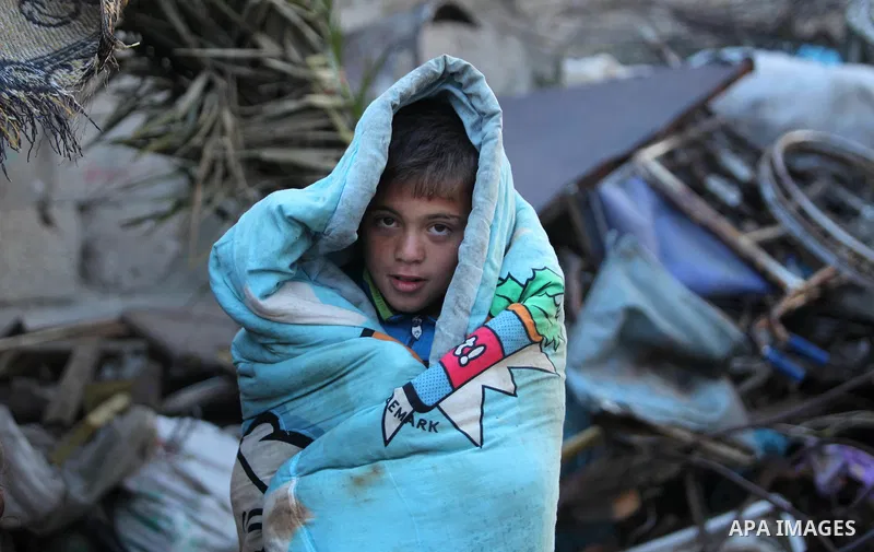 A Palestinian boy walks outside his family's shanty during the winter storm in Khan Younis, in the southern Gaza Strip on December 14, 2016. Photo by Ashraf Amra