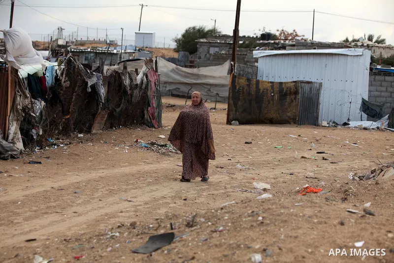 A Palestinian woman walks outside her dwelling during the winter storm in Khan Younis, in the southern Gaza Strip on December 14, 2016. Photo by Ashraf Amra