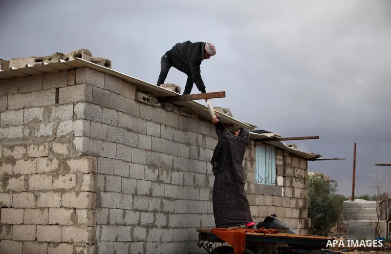 A Palestinian man and his wife repair their dwelling during the winter storm in Khan Younis, in the southern Gaza Strip on December 14, 2016. Photo by Ashraf Amra