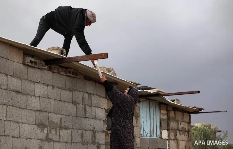A Palestinian man and his wife repair their dwelling during the winter storm in Khan Younis, in the southern Gaza Strip on December 14, 2016. Photo by Ashraf Amra
