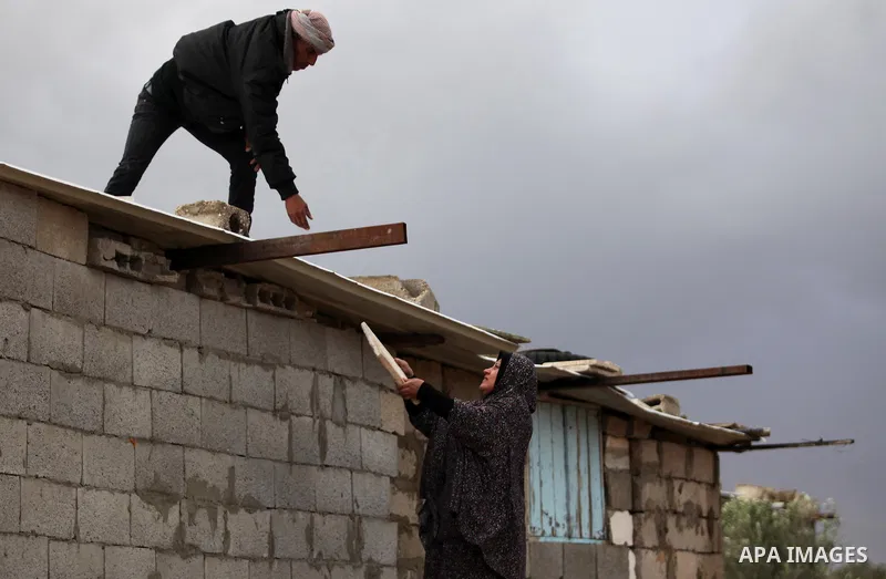 A Palestinian man and his wife repair their dwelling during the winter storm in Khan Younis, in the southern Gaza Strip on December 14, 2016. Photo by Ashraf Amra