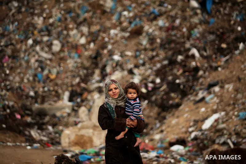 A Palestinian woman holds her child at their dwelling during the winter storm in Khan Younis, in the southern Gaza Strip on December 14, 2016. Photo by Ashraf Amra