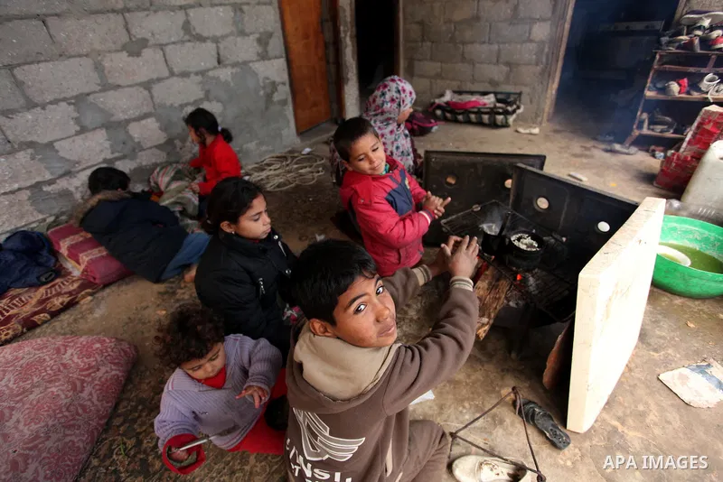 Palestinians warm themselves around a fire during the winter storm in Khan Younis, in the southern Gaza Strip on December 14, 2016. Photo by Ashraf Amra