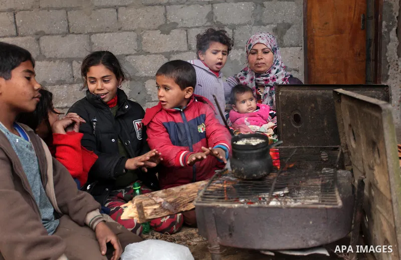 Palestinians warm themselves around a fire during the winter storm in Khan Younis, in the southern Gaza Strip on December 14, 2016. Photo by Ashraf Amra