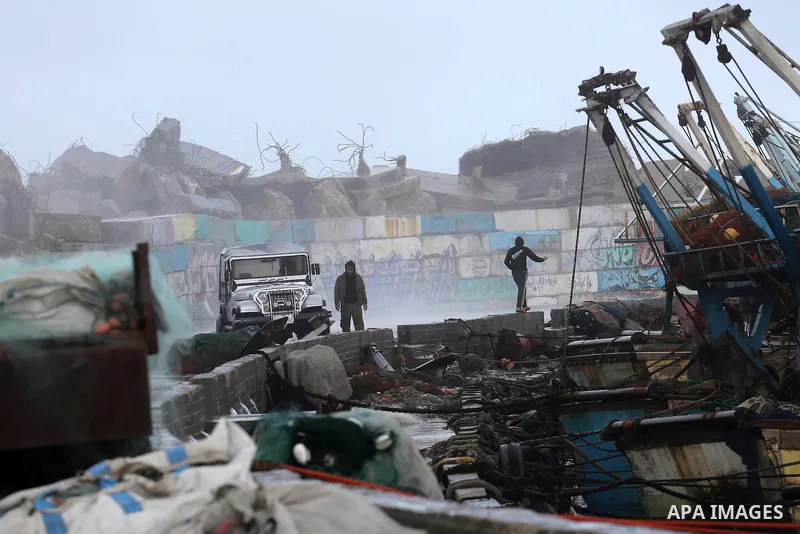 Palestinain men stand at the Gaza seaport during a stormy day, in Gaza city on December 14, 2016. Photo by Mohammed Asad