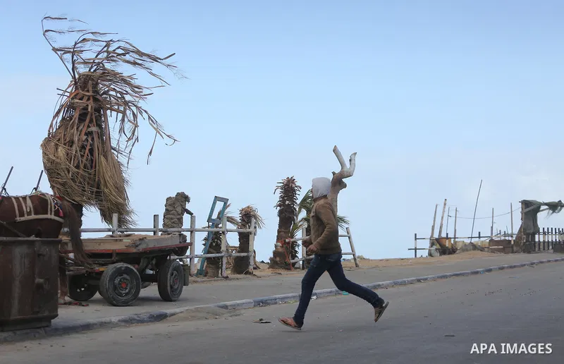 Palestininas walk at a street during a stormy day, in Gaza city on December 14, 2016. Photo by Mohammed Asad