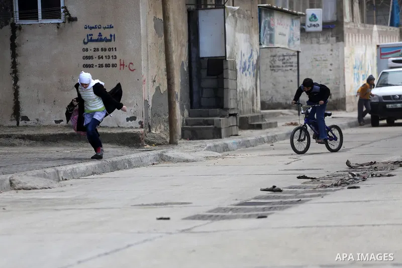 Palestininas walk at a street during a stormy day, in Gaza city on December 14, 2016. Photo by Mohammed Asad