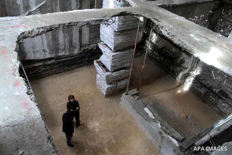 Dutch artist Marjan Teeuwen speaks with her assistant as she creates an architectural work that involves re-assembling wreckage of a house, that was destroyed during 2014, and turning it into artistic structures, in Khan...