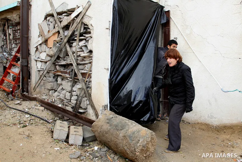 Dutch artist Marjan Teeuwen speaks with her assistant as she creates an architectural work that involves re-assembling wreckage of a house, that was destroyed during 2014, and turning it into artistic structures, in Khan...