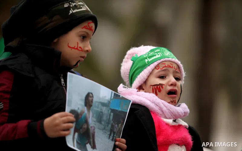 Palestinian children hold banners during a protest to solidarity with the inhabitants of the embattled Syrian city of Aleppo, in front of the high commissioner for human rights headquarters, in Gaza city, on December 15,...