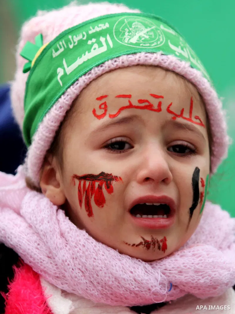 Palestinian children hold banners during a protest to solidarity with the inhabitants of the embattled Syrian city of Aleppo, in front of the high commissioner for human rights headquarters, in Gaza city, on December 15,...