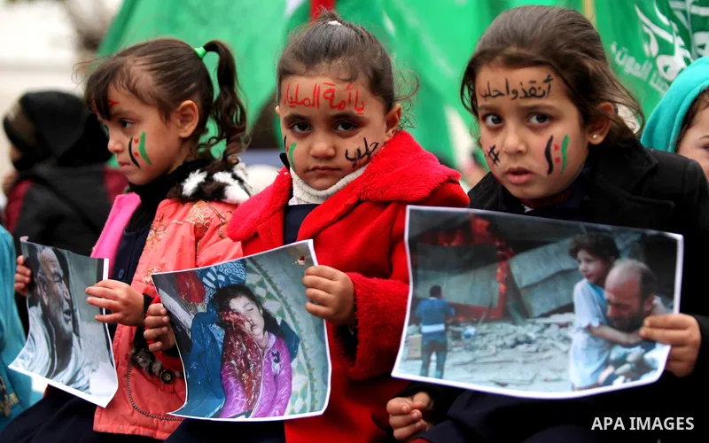 Palestinian children hold banners during a protest to solidarity with the inhabitants of the embattled Syrian city of Aleppo, in front of the high commissioner for human rights headquarters, in Gaza city, on December 15,...