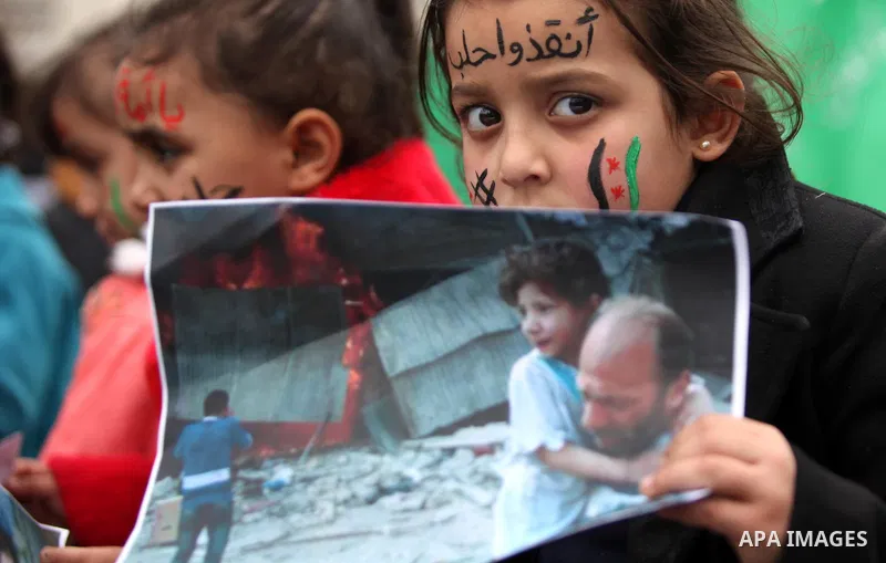 Palestinian children hold banners during a protest to solidarity with the inhabitants of the embattled Syrian city of Aleppo, in front of the high commissioner for human rights headquarters, in Gaza city, on December 15,...