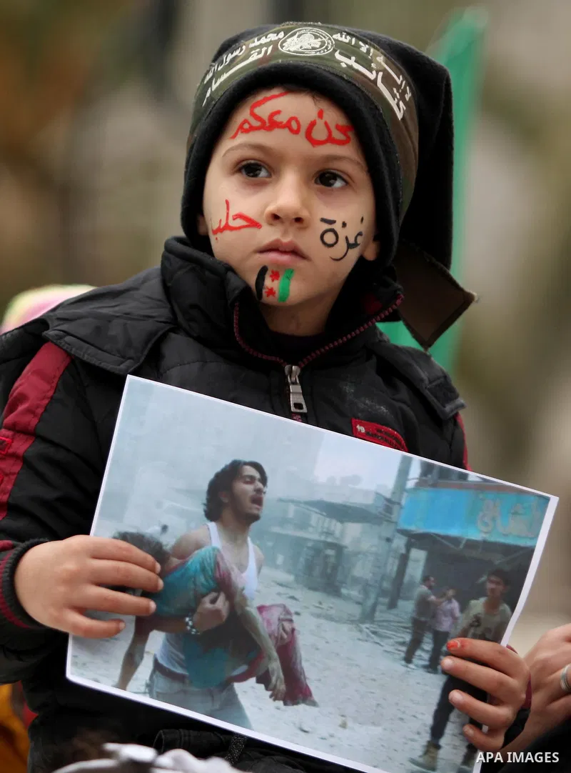 Palestinian children hold banners during a protest to solidarity with the inhabitants of the embattled Syrian city of Aleppo, in front of the high commissioner for human rights headquarters, in Gaza city, on December 15,...