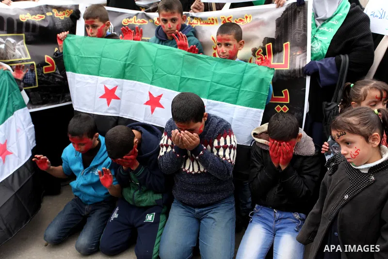 Palestinian children hold banners during a protest to solidarity with the inhabitants of the embattled Syrian city of Aleppo, in front of the high commissioner for human rights headquarters, in Gaza city, on December 15,...