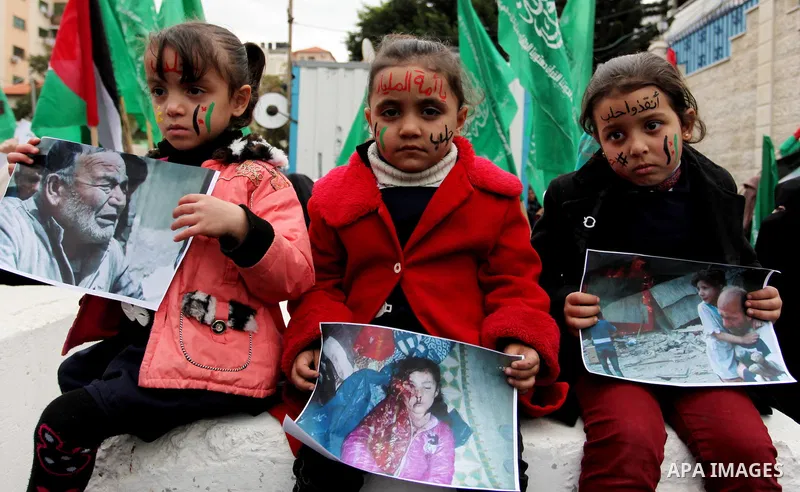 Palestinian children hold banners during a protest to solidarity with the inhabitants of the embattled Syrian city of Aleppo, in front of the high commissioner for human rights headquarters, in Gaza city, on December 15,...