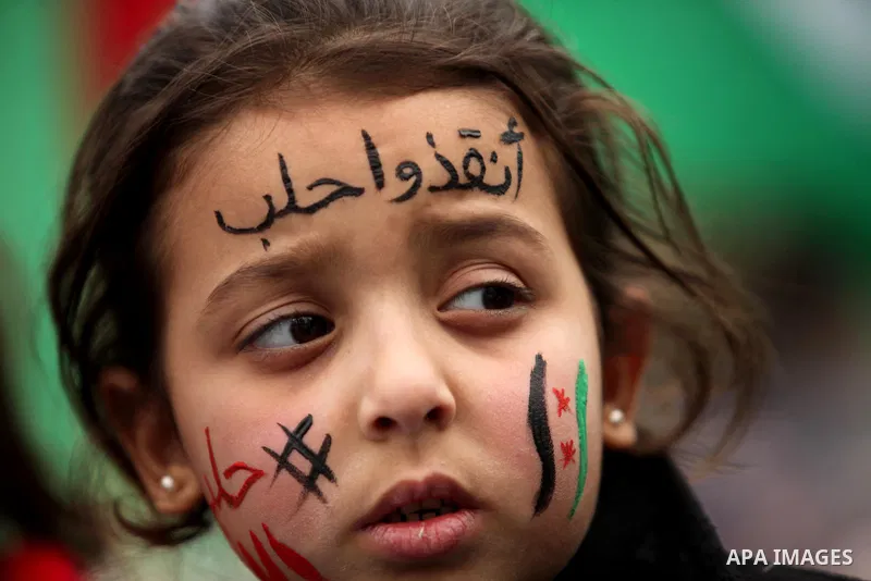 Palestinian children hold banners during a protest to solidarity with the inhabitants of the embattled Syrian city of Aleppo, in front of the high commissioner for human rights headquarters, in Gaza city, on December 15,...