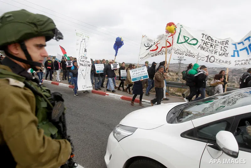 Peace activists hold placards during a joint Israeli-Palestinian peace march along the Israeli controversial separation wall in the West Bank city of Beit Jala between Bethlehem and Jerusalem, on December 16, 2016. Photo...