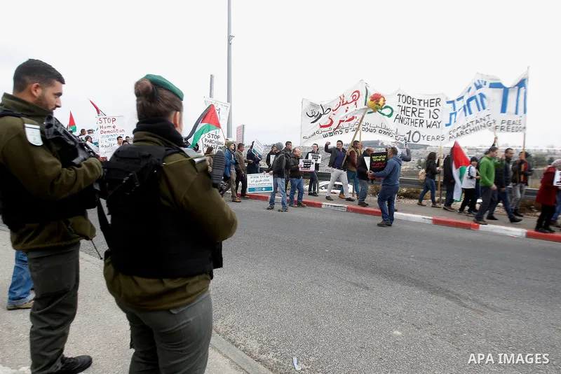 Peace activists hold placards during a joint Israeli-Palestinian peace march along the Israeli controversial separation wall in the West Bank city of Beit Jala between Bethlehem and Jerusalem, on December 16, 2016. Photo...