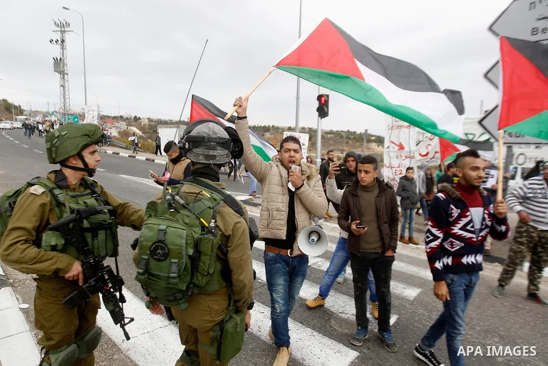 Peace activists hold placards during a joint Israeli-Palestinian peace march along the Israeli controversial separation wall in the West Bank city of Beit Jala between Bethlehem and Jerusalem, on December 16, 2016. Photo...