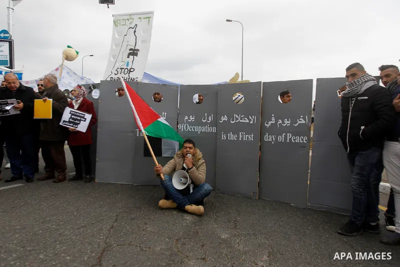 Peace activists hold placards during a joint Israeli-Palestinian peace march along the Israeli controversial separation wall in the West Bank city of Beit Jala between Bethlehem and Jerusalem, on December 16, 2016. Photo...