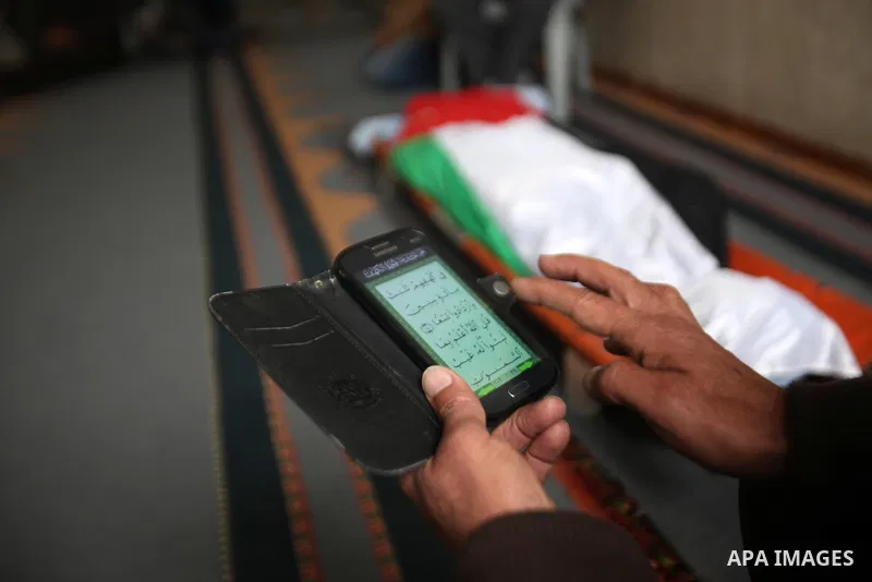 A man reads the Koran near the body of Palestinian Rahiq Birawi, who according to the Israeli police was shot dead after she had advanced towards them with a knife in her hand at a checkpoint last October, during her fun...