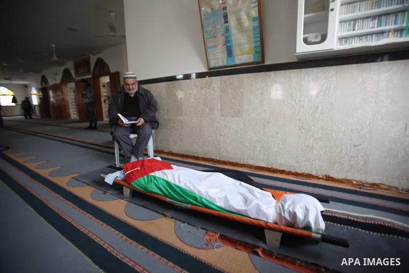 A man reads the Koran near the body of Palestinian Rahiq Birawi, who according to the Israeli police was shot dead after she had advanced towards them with a knife in her hand at a checkpoint last October, during her fun...
