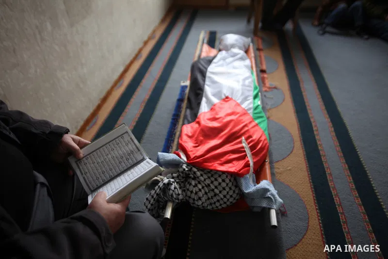 A man reads the Koran near the body of Palestinian Rahiq Birawi, who according to the Israeli police was shot dead after she had advanced towards them with a knife in her hand at a checkpoint last October, during her fun...