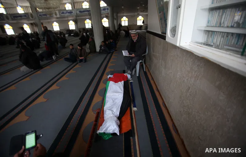A man reads the Koran near the body of Palestinian Rahiq Birawi, who according to the Israeli police was shot dead after she had advanced towards them with a knife in her hand at a checkpoint last October, during her fun...