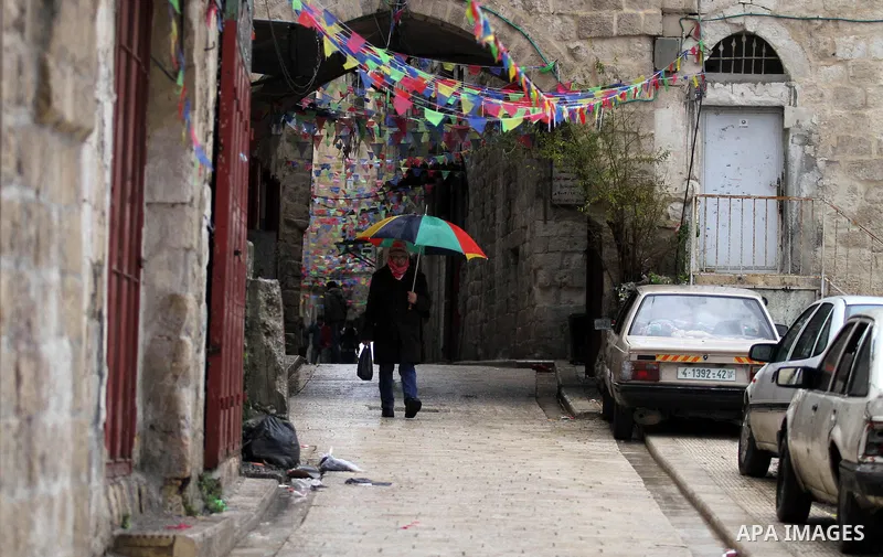 A Palestinian man walks with his umbrella under the rain, during a winter storm, in the West Bank city of Nablus, on December 18, 2016. Photo by Nedal Eshtayah