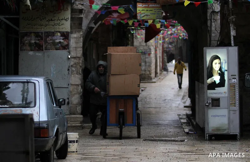 Palestinians walk under the rain, during a winter storm, in the West Bank city of Nablus, on December 18, 2016. Photo by Nedal Eshtayah