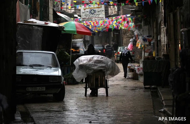 Palestinians walk under the rain, during a winter storm, in the West Bank city of Nablus, on December 18, 2016. Photo by Nedal Eshtayah