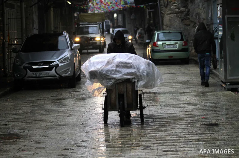 Palestinians walk under the rain, during a winter storm, in the West Bank city of Nablus, on December 18, 2016. Photo by Nedal Eshtayah