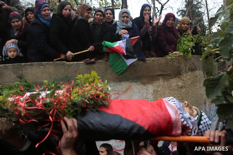 Mourners carry the body of Palestinian Ahmed al-Remawi, who Palestinian Health Ministry said was shot and killed by Israeli forces on Sunday, during his funeral in the West Bank village of Beit Rima near Ramallah Decembe...
