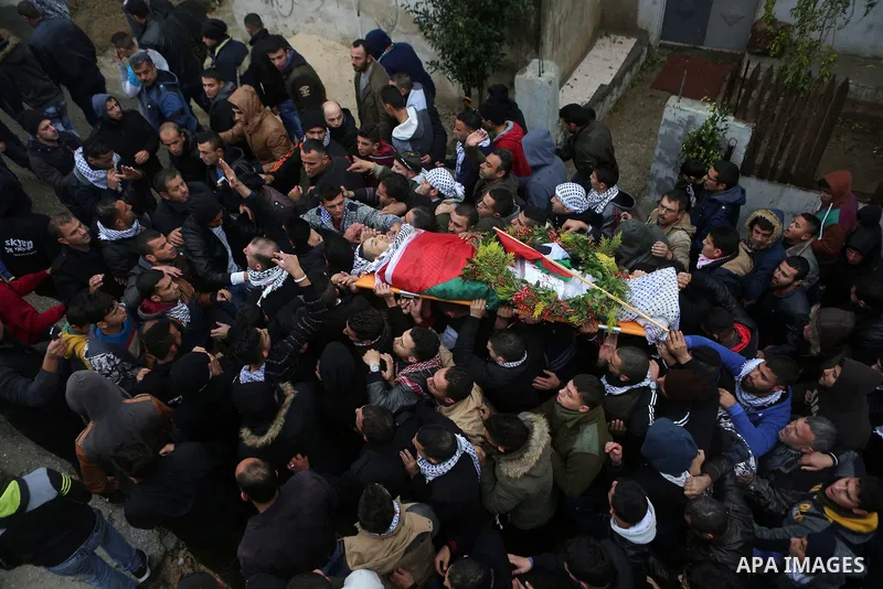 Mourners carry the body of Palestinian Ahmed al-Remawi, who Palestinian Health Ministry said was shot and killed by Israeli forces on Sunday, during his funeral in the West Bank village of Beit Rima near Ramallah Decembe...