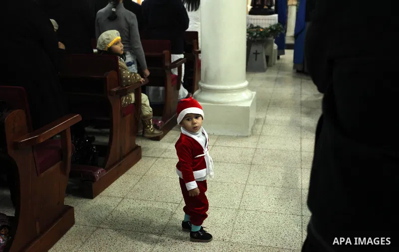 A Palestinian boy dressed as Santa Claus attends a mass ahead of Christmas at Der Latin church in Gaza City on December 18, 2016. Photo by Ashraf Amra