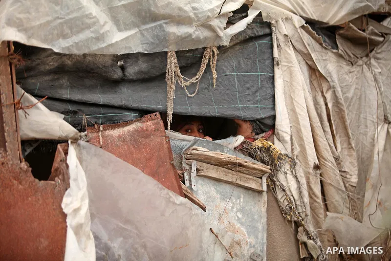 A Palestinian woman looks through her dwelling covered with plastic sheet in Khan Younis in the southern Gaza Strip December 19, 2016. Photo by Ashraf Amra