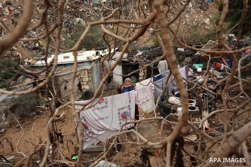 A Palestinian woman hangs laundry on a rope to dry outside her dwelling in Khan Younis in the southern Gaza Strip December 19, 2016. Photo by Ashraf Amra