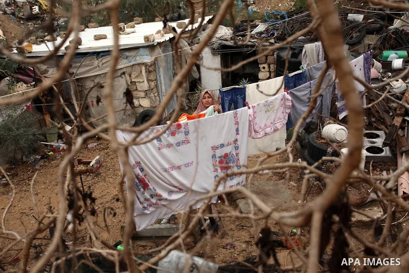 A Palestinian woman hangs laundry on a rope to dry outside her dwelling in Khan Younis in the southern Gaza Strip December 19, 2016. Photo by Ashraf Amra
